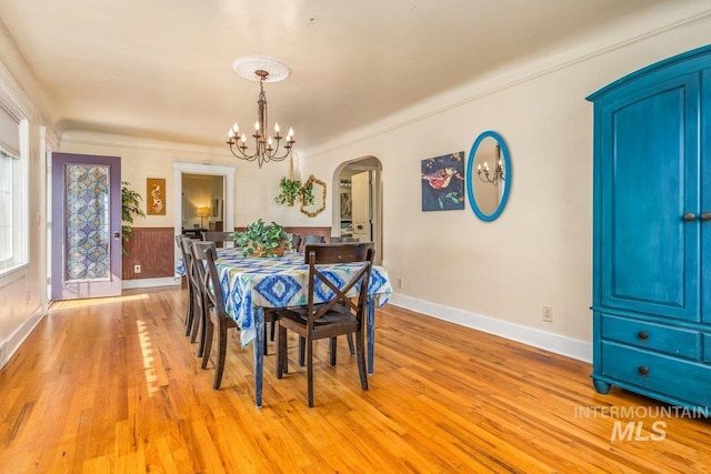 dining room featuring an inviting chandelier, light wood-style flooring, baseboards, and arched walkways