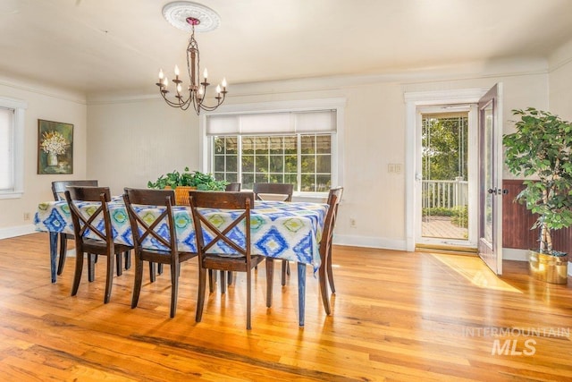 dining space featuring a notable chandelier, a healthy amount of sunlight, light wood-type flooring, and baseboards