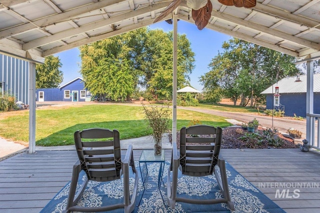 wooden terrace featuring ceiling fan and a yard