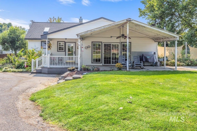 view of front of home featuring a front yard, a ceiling fan, a porch, a chimney, and a patio area