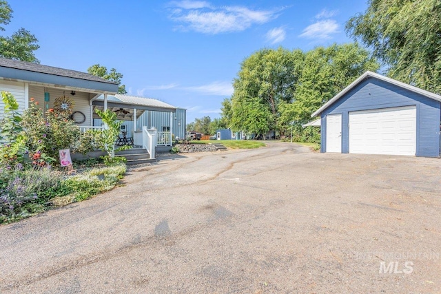 exterior space featuring an outbuilding, covered porch, driveway, and a detached garage