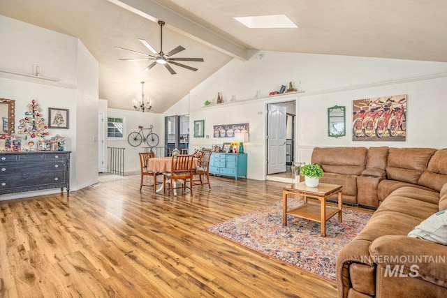 living area with beamed ceiling, ceiling fan with notable chandelier, a skylight, wood finished floors, and high vaulted ceiling