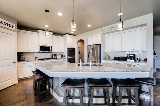 1234 W Sagwon Dr, Kuna, ID 83634 - kitchen with appliances with stainless steel finishes, backsplash, recessed lighting, arched walkways, and a breakfast bar