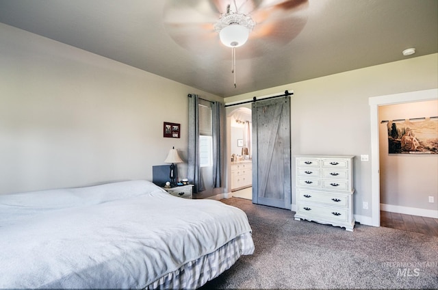 1234 W Sagwon Dr, Kuna, ID 83634 - bedroom featuring a barn door, dark carpet, baseboards, ensuite bathroom, and a ceiling fan
