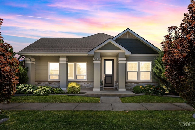10685 W Evelia St, Boise, ID 83709 - view of front of house with stone siding, a front yard, a shingled roof, and a porch
