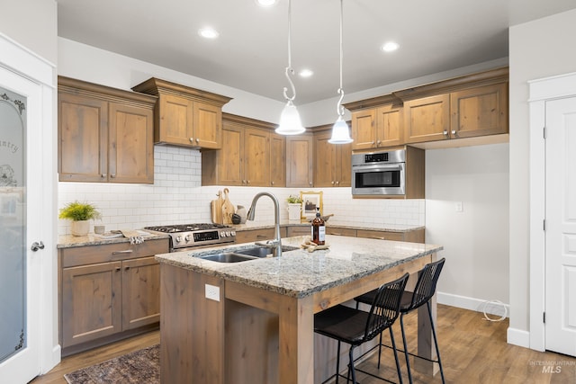 10685 W Evelia St, Boise, ID 83709 - kitchen featuring appliances with stainless steel finishes, light stone countertops, decorative backsplash, dark wood finished floors, and recessed lighting