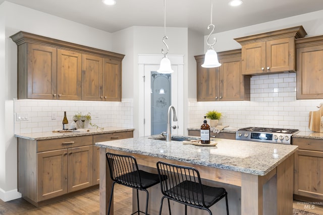 10685 W Evelia St, Boise, ID 83709 - kitchen with an island with sink, tasteful backsplash, light stone counters, light wood-style floors, and recessed lighting