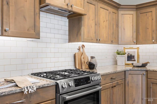 10685 W Evelia St, Boise, ID 83709 - kitchen with stainless steel gas stove, under cabinet range hood, decorative backsplash, and light stone counters