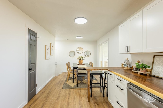 kitchen featuring white cabinetry, butcher block countertops, dishwasher, and light wood-type flooring