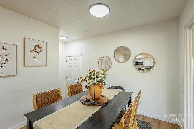 dining area with wood-type flooring and a textured ceiling