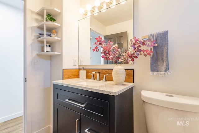 bathroom with toilet, vanity, and hardwood / wood-style floors