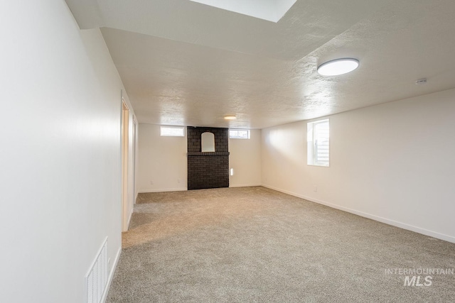 basement with carpet floors, a brick fireplace, and a textured ceiling