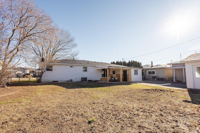 rear view of house with cooling unit, a lawn, and a patio