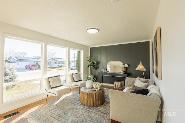 sitting room with a healthy amount of sunlight, wood walls, a textured ceiling, and hardwood / wood-style flooring