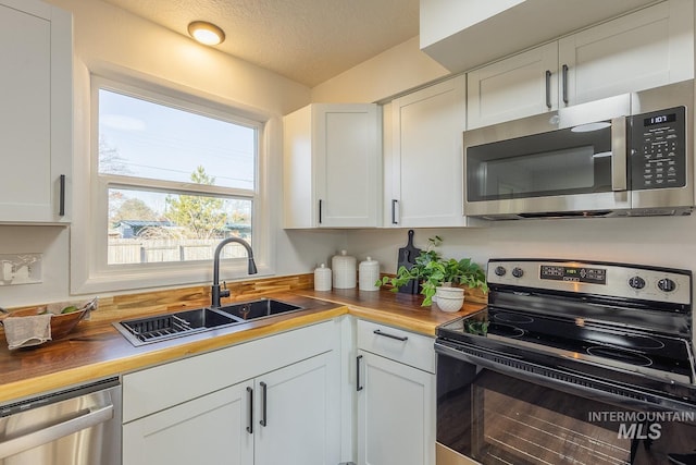 kitchen featuring white cabinets, stainless steel appliances, and wood counters