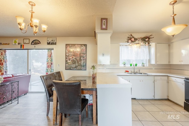 kitchen featuring hanging light fixtures, kitchen peninsula, sink, and white cabinets