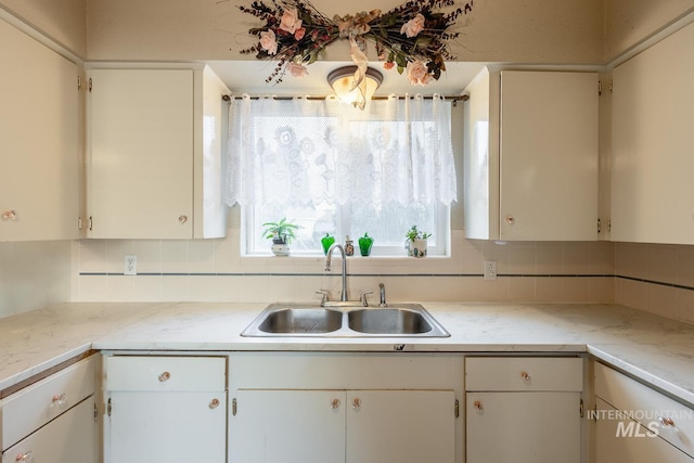 kitchen featuring sink, white cabinets, and backsplash