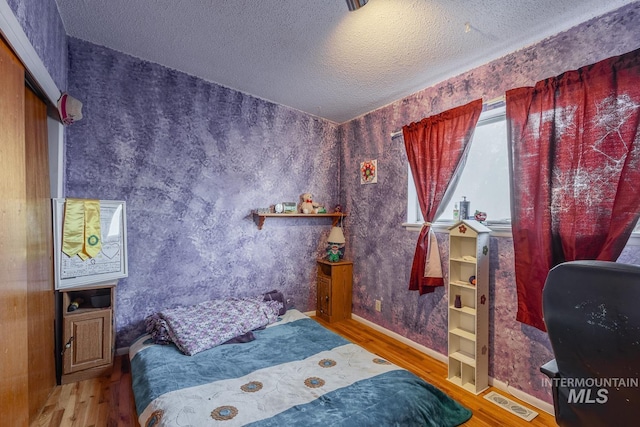 bedroom with hardwood / wood-style floors and a textured ceiling