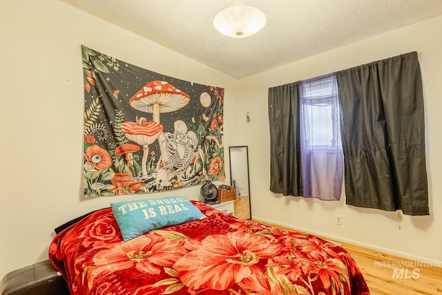 bedroom with vaulted ceiling, hardwood / wood-style floors, and a textured ceiling