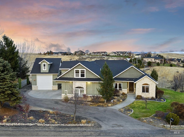 view of front of house with a garage, stone siding, a lawn, and concrete driveway