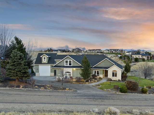 view of front facade with driveway, stone siding, a garage, and a residential view