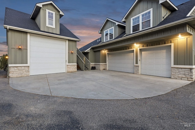 view of property exterior with driveway, stone siding, stairway, and board and batten siding