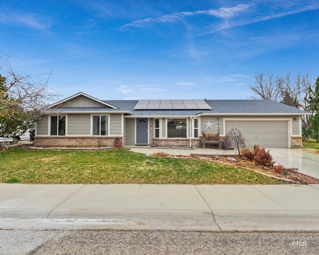 ranch-style home featuring a front yard, driveway, an attached garage, brick siding, and roof mounted solar panels