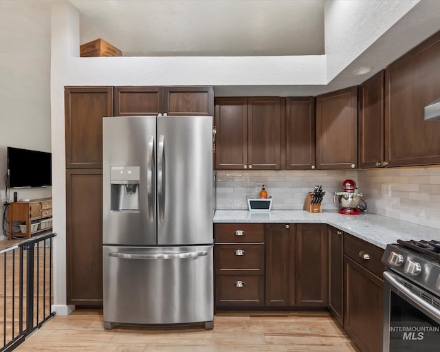 kitchen featuring light wood-type flooring, backsplash, and appliances with stainless steel finishes