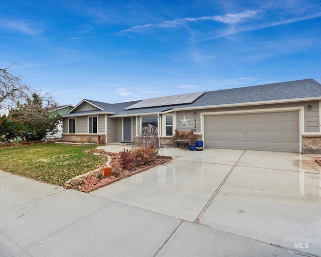 single story home with driveway, a shingled roof, a front yard, an attached garage, and solar panels