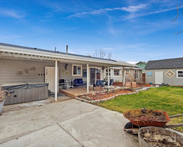 rear view of house featuring a patio, a lawn, an outdoor structure, and a hot tub