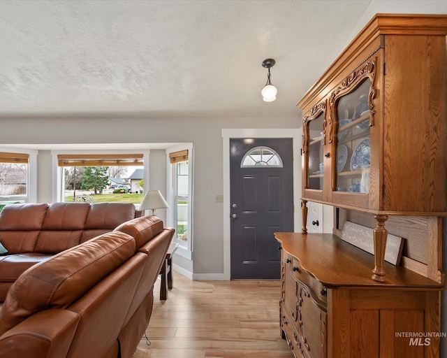 foyer entrance featuring light wood-style flooring, baseboards, and a textured ceiling