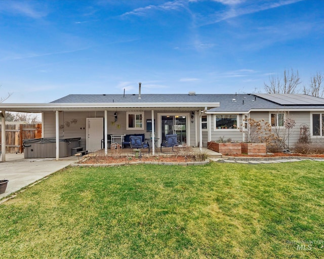 back of property with a patio area, a hot tub, a yard, and fence