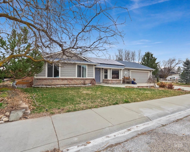 ranch-style home with an attached garage, a front lawn, concrete driveway, brick siding, and roof mounted solar panels