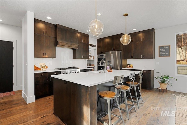 kitchen featuring a sink, stainless steel appliances, light wood-style flooring, and light countertops