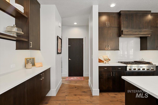 kitchen featuring open shelves, dark brown cabinetry, stainless steel gas stovetop, and light countertops