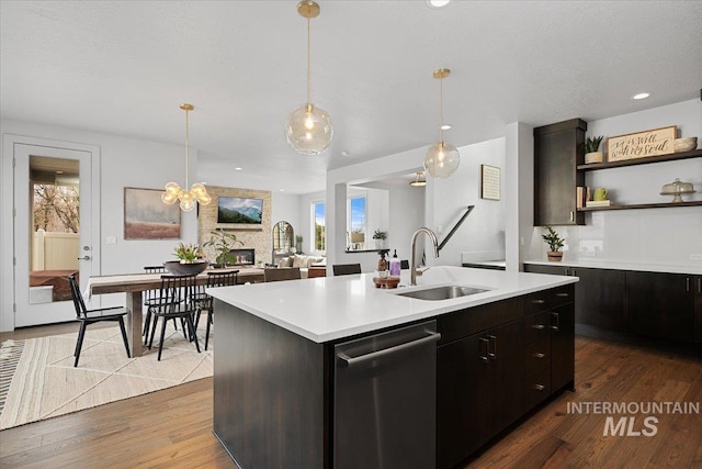 kitchen featuring dark wood finished floors, a kitchen island with sink, a sink, light countertops, and dishwasher