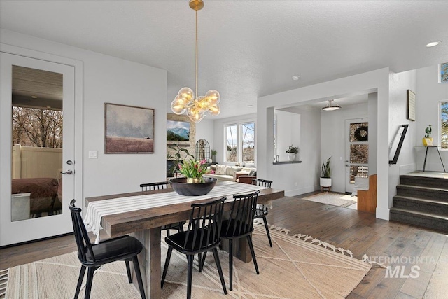 dining area featuring light wood-style flooring, recessed lighting, an inviting chandelier, baseboards, and stairs