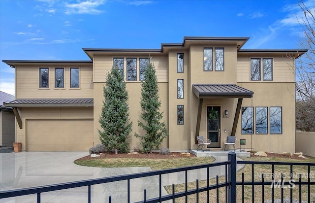 prairie-style home with a fenced front yard, stucco siding, metal roof, driveway, and a standing seam roof