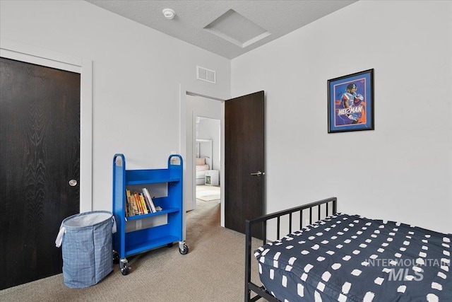 bedroom featuring attic access, carpet flooring, visible vents, and a textured ceiling