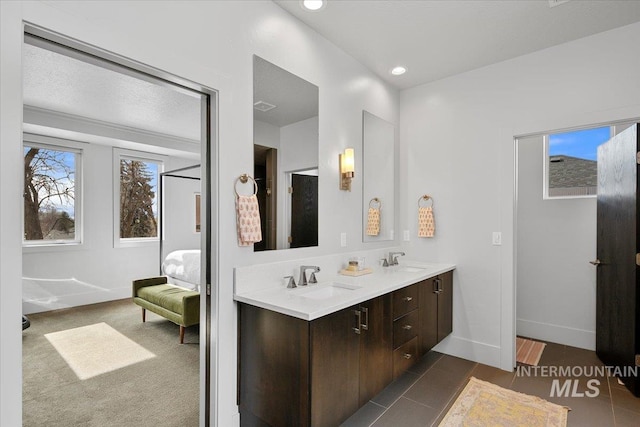 bathroom with baseboards, double vanity, recessed lighting, a sink, and ensuite bathroom