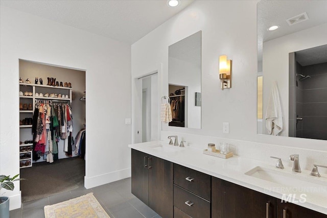 bathroom with a sink, visible vents, double vanity, and a spacious closet