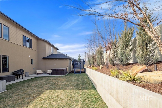 view of yard featuring a hot tub, a trampoline, fence, central AC unit, and a patio