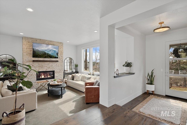 living room with a stone fireplace, recessed lighting, baseboards, and wood-type flooring