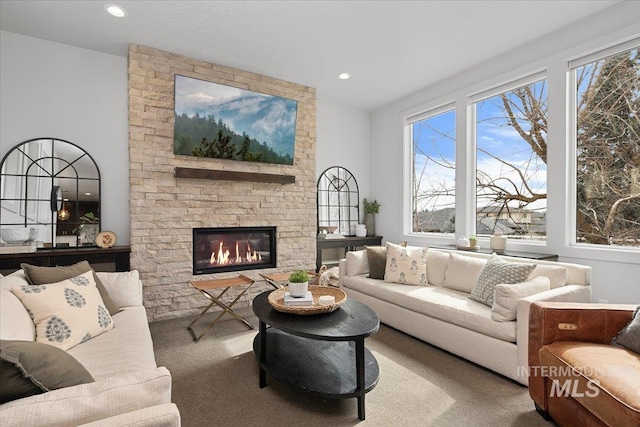 living room with a wealth of natural light, a stone fireplace, carpet flooring, and recessed lighting