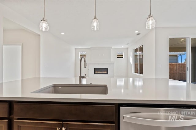 kitchen featuring pendant lighting, stainless steel dishwasher, sink, and dark brown cabinets