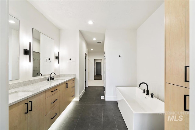 full bathroom featuring double vanity, tile patterned floors, a freestanding bath, a sink, and recessed lighting