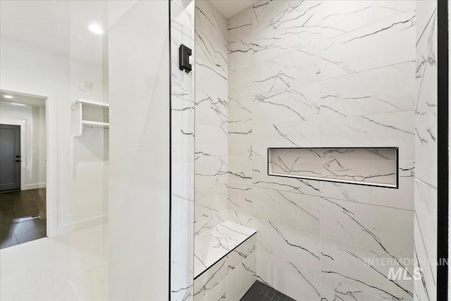 bathroom with a marble finish shower and baseboards