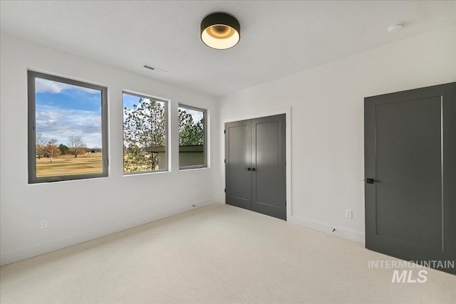 unfurnished bedroom featuring a closet, carpet flooring, visible vents, and baseboards