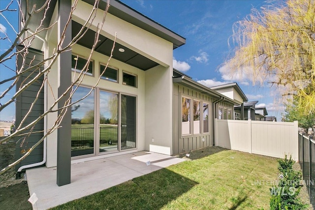 exterior space with a lawn, a patio area, fence, and stucco siding