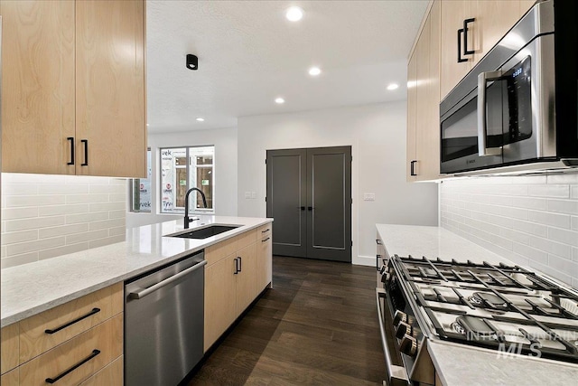 kitchen with dark wood-style floors, light brown cabinets, appliances with stainless steel finishes, and a sink